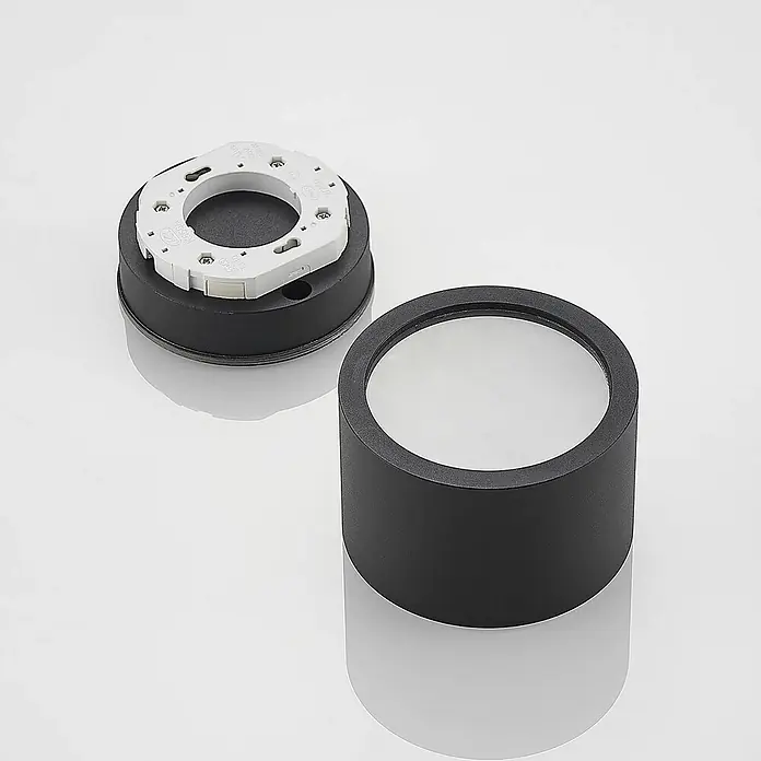 Arcchio Deckenstrahler Nieva - L x B x H: 10 x 10 x 6,5 cm, schwarz, schwarz, 2GX53 - Schwarze zylindrische LED-Einbauleuchte, zerlegt. Zeigt Montagefuß mit weißem Elektroanschluss und Gehäuse mit mattem Diffusor.