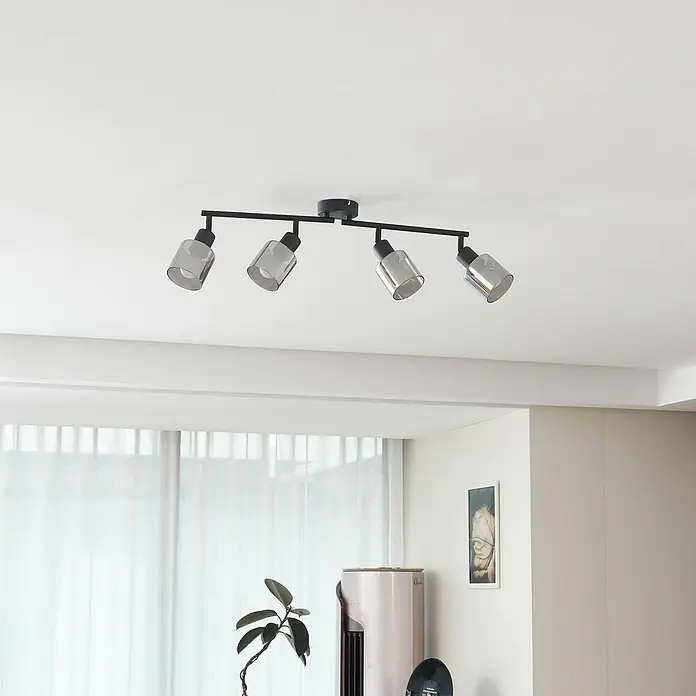 Lindby Deckenstrahler Netty - schwarz, alu / grau / zink, E14 - Schwarze 4-flammige Deckenleuchte mit grauen Glasschirmen, an Decke montiert, beleuchtet ein modernes Zimmer.
