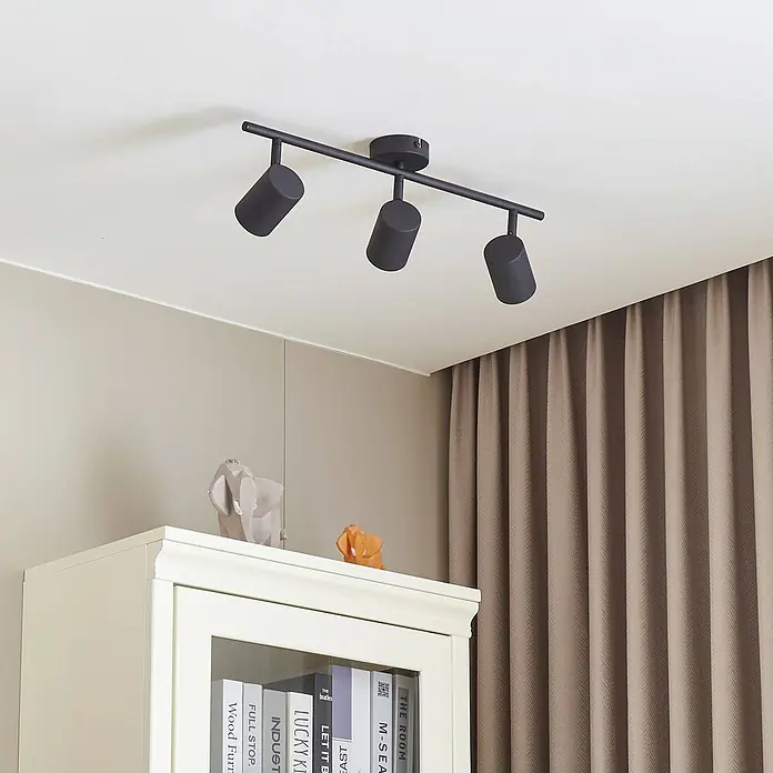Lindby Deckenstrahler Jorell - L x B x H: 50,5 x 8 x 15,5 cm, schwarz, schwarz, GU10 - Schwarzer Deckenstrahler mit drei verstellbaren zylindrischen Köpfen an einer Stange, beleuchtet einen Raum mit neutraler Einrichtung.