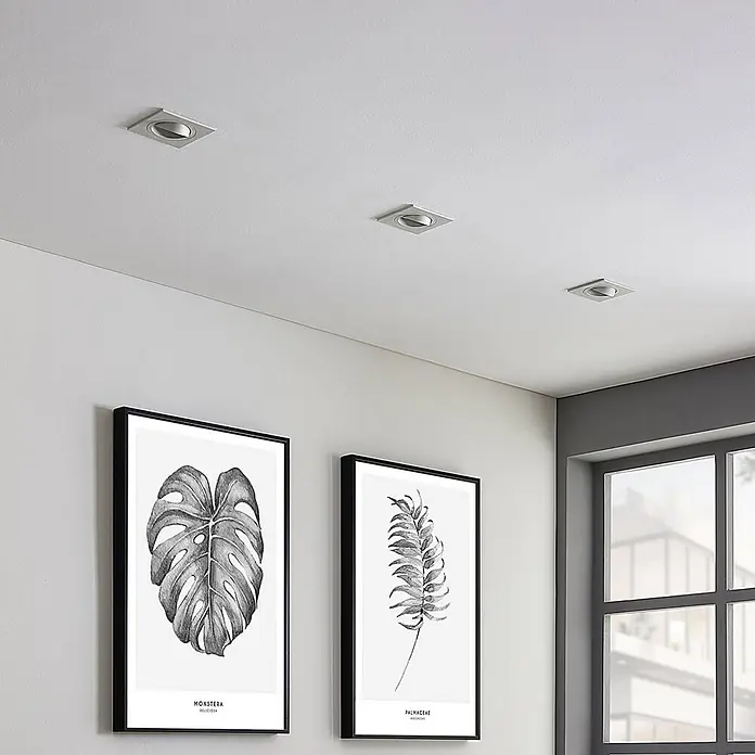 Arcchio Deckenstrahler Sophia - weiß / opal, GU10 - Quadratische, silberfarbene Einbaustrahler in einer weißen Decke, die einen Raum mit botanischer Kunst beleuchten.