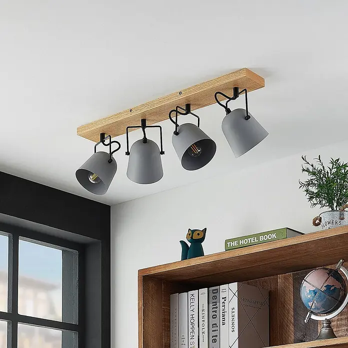 Lindby Deckenstrahler Adalin - Holz hell, alu / grau / zink, E14 - Deckenleuchte mit Holzbalken und vier grauen verstellbaren Strahlern, die einen Raum mit Regal beleuchtet.