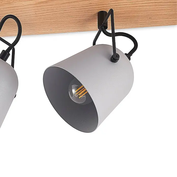Lindby Deckenstrahler Adalin - Holz hell, alu / grau / zink, E14 - Zwei graue Metallstrahler an einer hellen Holzleiste mit schwarzen geflochtenen Kabeln und sichtbaren Glühfadenlampen.