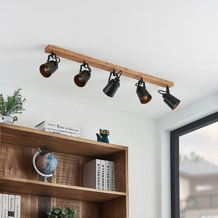 Lindby Deckenstrahler Kimban - L x B x H: 106,5 x 8,3 x 15,8 cm, Holz dunkel, schwarz, E14 - Deckenstrahler mit Holzleiste und fünf schwarzen Metallspots, an weißer Decke über Holzregal montiert.