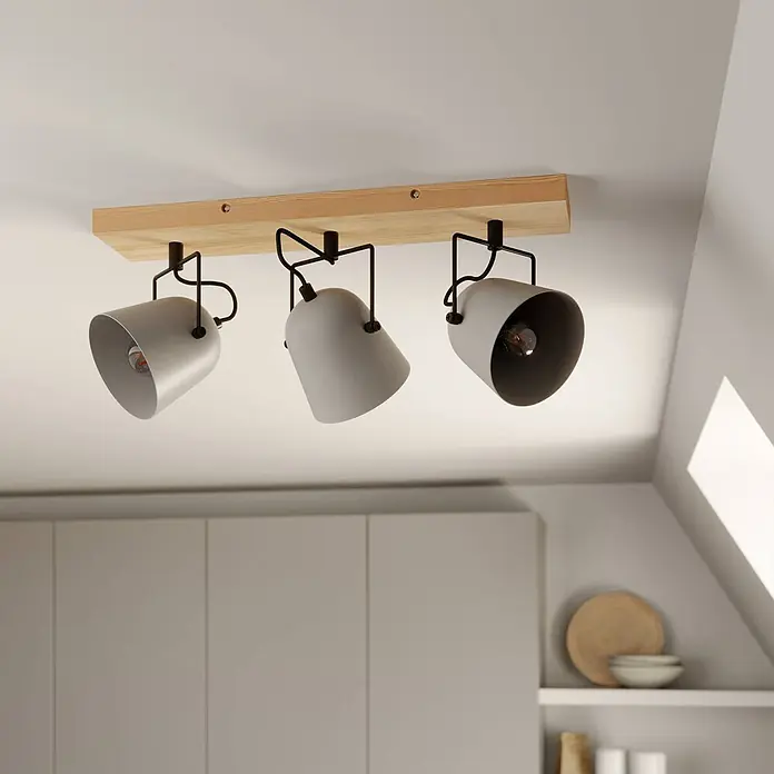 Lindby Deckenstrahler Adalin - Holz hell, alu / grau / zink, E14 - Drei hellgraue Strahler mit schwarzen Rahmen an einem hellen Holzdeckenbalken, die einen modernen Raum beleuchten.