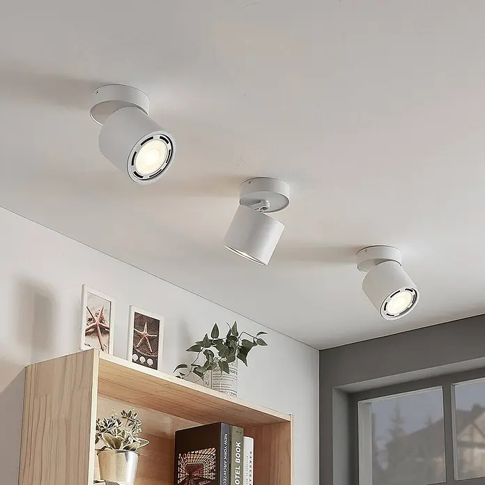 Arcchio Deckenstrahler Mabel - weiß / opal, weiß / opal, GU10 - Drei moderne, weiße, verstellbare Deckenstrahler beleuchten einen Raum und heben ein Holzregal hervor.