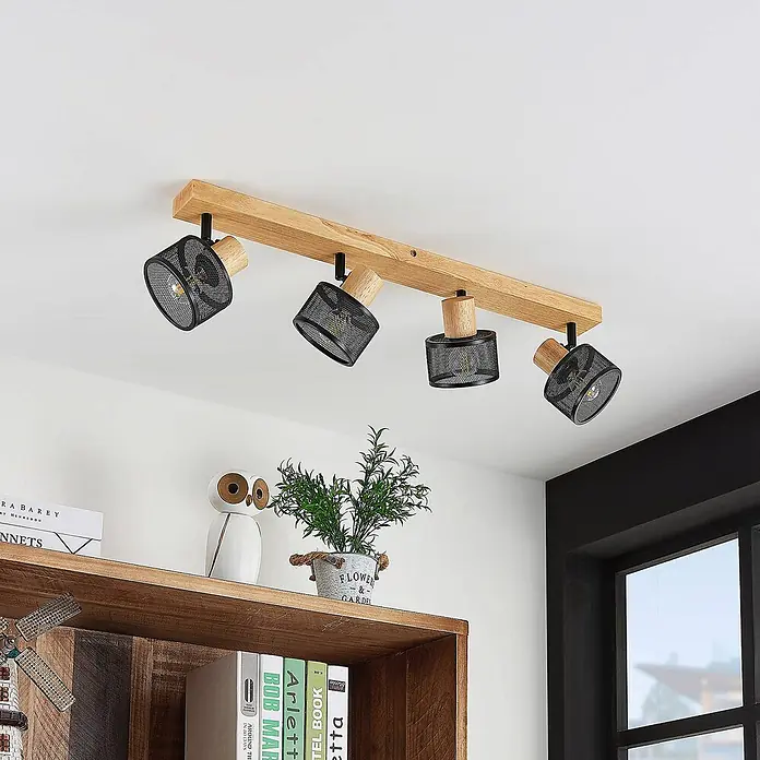 Lindby Deckenstrahler Evinora - Holz dunkel, schwarz, E14 - Deckenstrahler mit Holzbalken und vier schwarzen Gitterlampen, über einem Regal montiert.