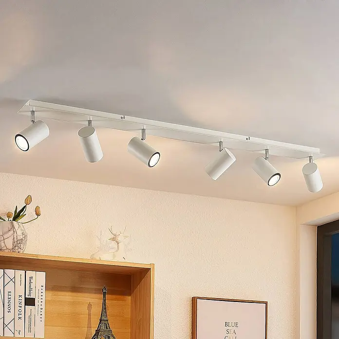Lindby Deckenstrahler Joffrey - L x B x H: 116 x 9 x 16,5 cm, weiß / opal, weiß / opal, GU10 - Weiße Deckenstrahlerleiste mit sechs verstellbaren zylindrischen Strahlern über einem Regal.