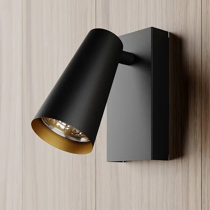 Lucande Deckenstrahler Angelina - schwarz, schwarz, GU10 - Schwarze zylindrische Wandleuchte mit goldener Innenseite, montiert an heller Holzverkleidung.