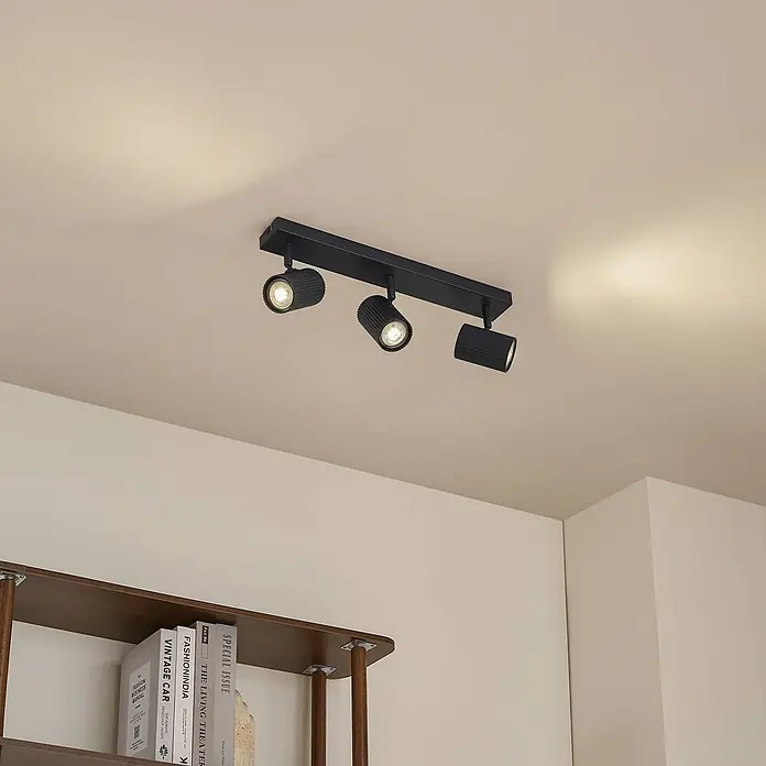 Lindby Deckenstrahler Kardis - L x B x H: 45 x 6 x 16 cm, alu / grau / zink, alu / grau / zink, GU10 - Schwarze Deckenleuchte mit drei Strahlern, montiert an der Decke, zwei Lichter an, beleuchtet den Bereich über einem Regal.