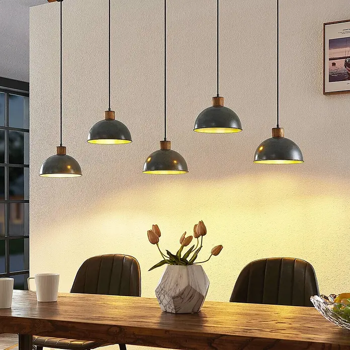 Lindby Pendelleuchte Durbis - L x B x H: 149 x 25 x 180 cm, schwarz, Holz natur, dunkelgrau, E27 - Fünf Pendelleuchten im Industriestil mit grauen Metallschirmen und Holzdetails beleuchten einen langen Holzesstisch.