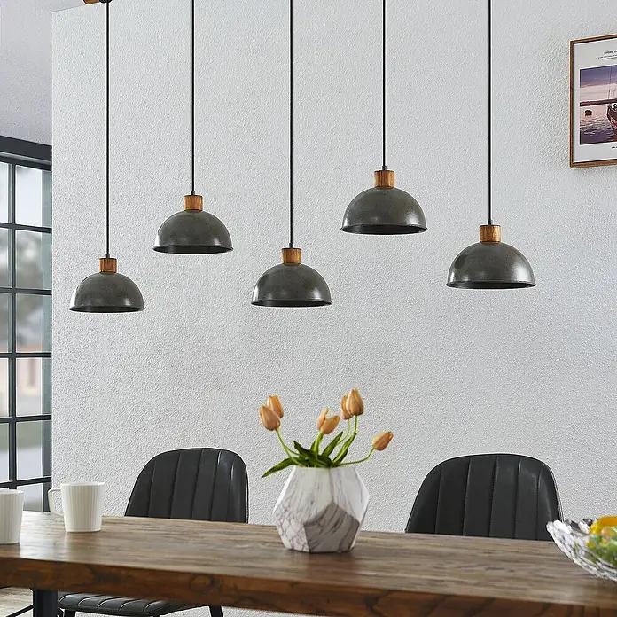 Lindby Pendelleuchte Durbis - L x B x H: 149 x 25 x 180 cm, schwarz, Holz natur, dunkelgrau, E27 - Fünf industrielle Pendelleuchten mit dunkelgrauen Metallschirmen und Holzdetails hängen über einem Esstisch.
