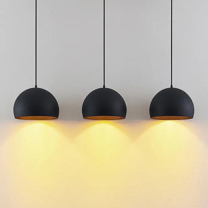 Lindby Pendelleuchte Tarjei - schwarz, Schwarz, gold, E27 - Drei schwarze Pendelleuchten mit goldenem Inneren hängen und werfen warmes Licht nach unten.