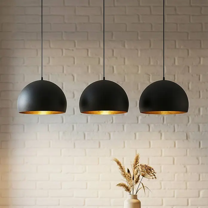 Lindby Pendelleuchte Tarjei - schwarz, Schwarz, gold, E27 - Drei matte schwarze kuppelförmige Pendelleuchten mit goldener Innenseite, nebeneinander hängend.