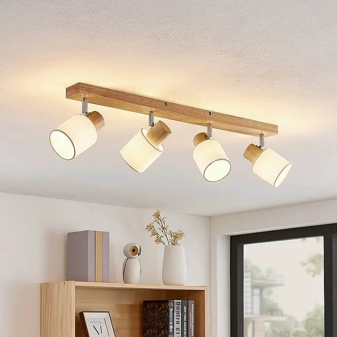 Lindby Deckenstrahler Wanessa - Holz hell, E14 - Deckenstrahler mit vier Spots, Holzleiste und weißen zylindrischen Schirmen mit Holzaufsatz, an der Decke montiert.