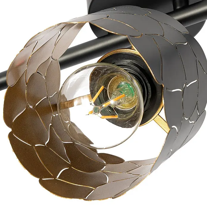 Lindby Deckenstrahler Aralena - schwarz, schwarz, E27 - Nahaufnahme eines schwarzen und goldfarbenen Metall-Lampenschirms mit Blattausschnitten, der eine klare LED-Glühbirne zeigt.
