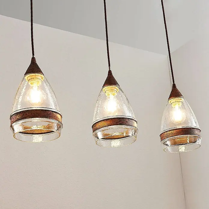 Lindby Pendelleuchte Millina - L x B x H: 70,4 x 15,6 x 25,8 cm, klar / transparent, rostbraun, klar, E27 - Drei Pendelleuchten mit gehämmerten Glasschirmen und rustikalen Bronzeakzenten, beleuchtet.