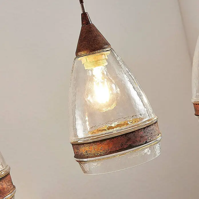 Lindby Pendelleuchte Millina - L x B x H: 70,4 x 15,6 x 25,8 cm, klar / transparent, rostbraun, klar, E27 - Beleuchtete Pendelleuchte mit klarem, strukturiertem Glasschirm und antikem bronzefarbenem Metallgestell.