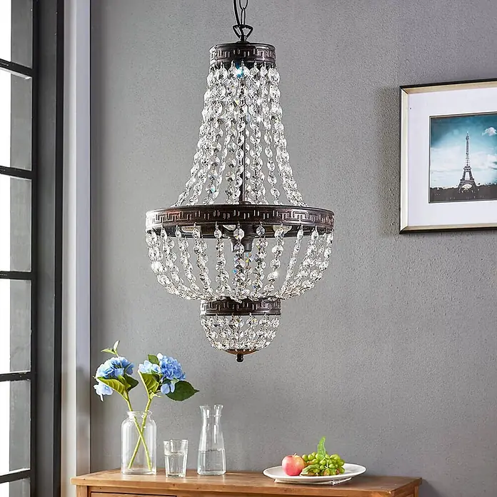 Lindby Pendelleuchte Jorve - L x B x H: 35 x 35 x 150 cm, klar / transparent, Schwarz gold gebürstet, klar, G9 - Ein eleganter, mehrstufiger Kronleuchter mit bronzefarbenem Metallgestell und klaren Kristallperlen hängt von der Decke und verleiht dem Raum Glanz.