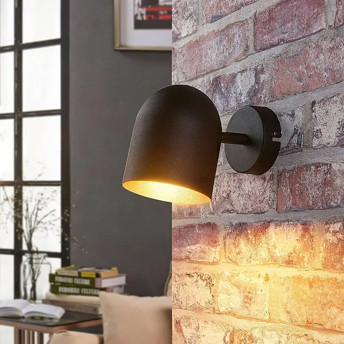 Lindby Deckenstrahler Morik - L x B x H: 19 x 10 x 12 cm, schwarz, schwarz, E14 - Schwarze Wandlampe mit goldenem Interieur, an einer Ziegelwand montiert, wirft warmes Licht.
