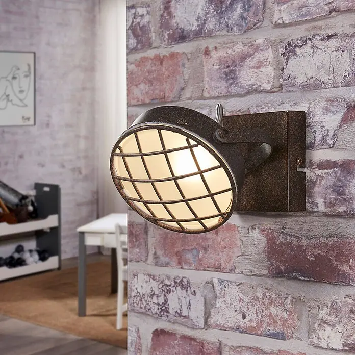 Lindby Deckenstrahler Tamin - L x B x H: 18 x 13 x 13 cm, braun / rost, braun / rost, G9 - Rostfarbene Wandleuchte mit Schutzgitter aus dunklem Metall, an Ziegelwand montiert und beleuchtet.