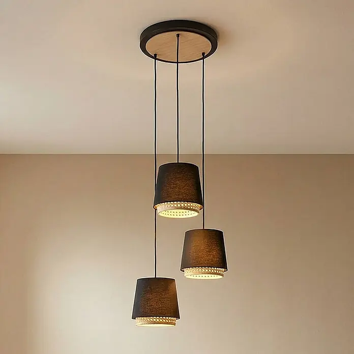 Lindby Pendelleuchte Ananya - L x B x H: 43 x 43 x 150 cm, schwarz, Schwarz, holz hell, E27 - Drei schwarze Stoff-Pendelleuchten mit Holzdetails hängen von einer runden Deckenhalterung und beleuchten einen Raum.