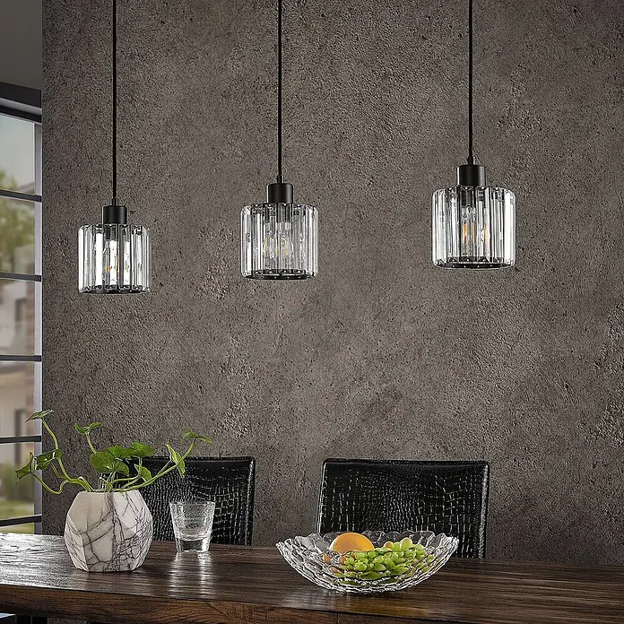 Lindby Pendelleuchte Vella - L x B x H: 83 x 13 x 12,3 cm, klar / transparent, mattSchwarz, transparent, E27 - Drei moderne Pendelleuchten mit klaren geriffelten Glasschirmen und schwarzen Akzenten über einem Esstisch.
