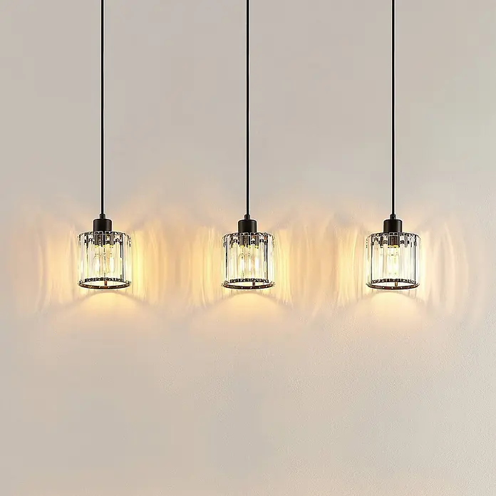 Lindby Pendelleuchte Vella - L x B x H: 83 x 13 x 12,3 cm, klar / transparent, mattSchwarz, transparent, E27 - Drei elegante Pendelleuchten mit klaren gerippten Glasschirmen und schwarzen Metallfassungen, die dekorative Lichtmuster werfen.
