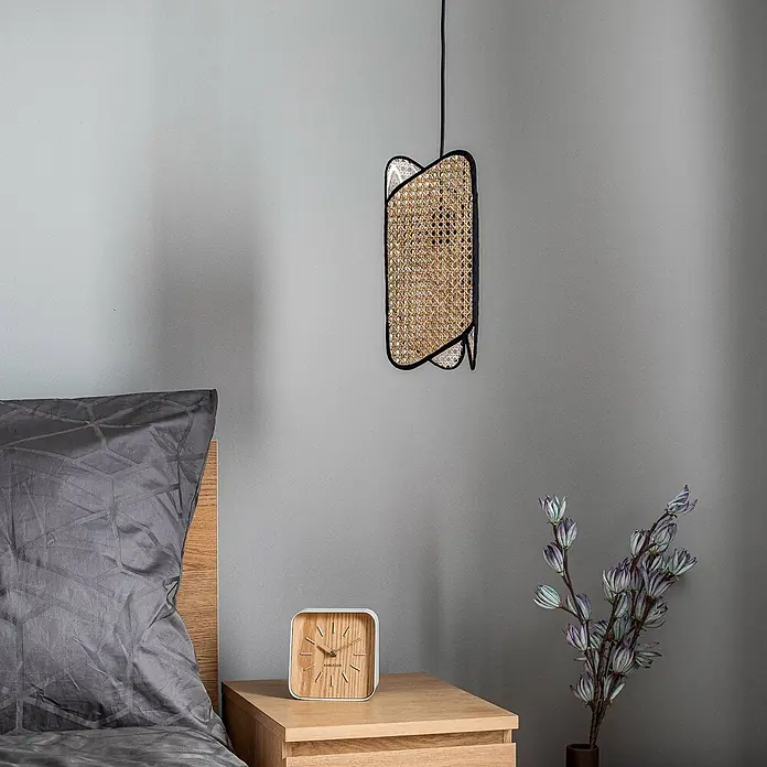 Lucande Pendelleuchte Bassiola - L x B x H: 19 x 19 x 37 cm, Holz hell, Schwarz, Holz hell, E27 - Wandlampe aus schwarzem Metall und Rattan, über einem Nachttisch montiert.