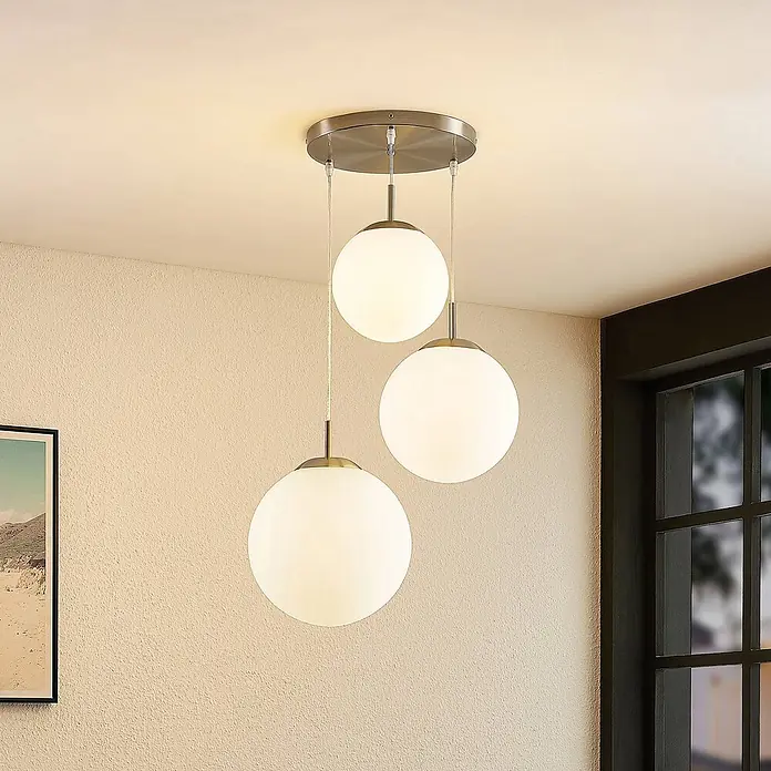 Lindby Pendelleuchte Heleska - weiß / opal, nickel matt, opalweiß, E27 - Dreiflammige Pendelleuchte mit opalweißen Glaskugeln und gebürsteten Metalldetails, beleuchtet einen Raum.
