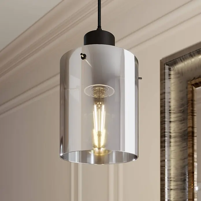 Lindby Pendelleuchte Kourtney - L x B x H: 15 x 15 x 18 cm, alu / grau / zink, Schwarz, rauchgrau, E27 - Zylindrische Pendelleuchte aus Rauchglas mit sichtbarer Edison-Glühbirne, in einem Raum hängend.