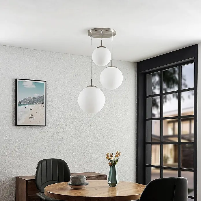 Lindby Pendelleuchte Heleska - weiß / opal, nickel matt, opalweiß, E27 - Dreiflammige Pendelleuchte mit mattweißen Kugelschirmen und gebürsteten Metallakzenten über einem Holztisch.