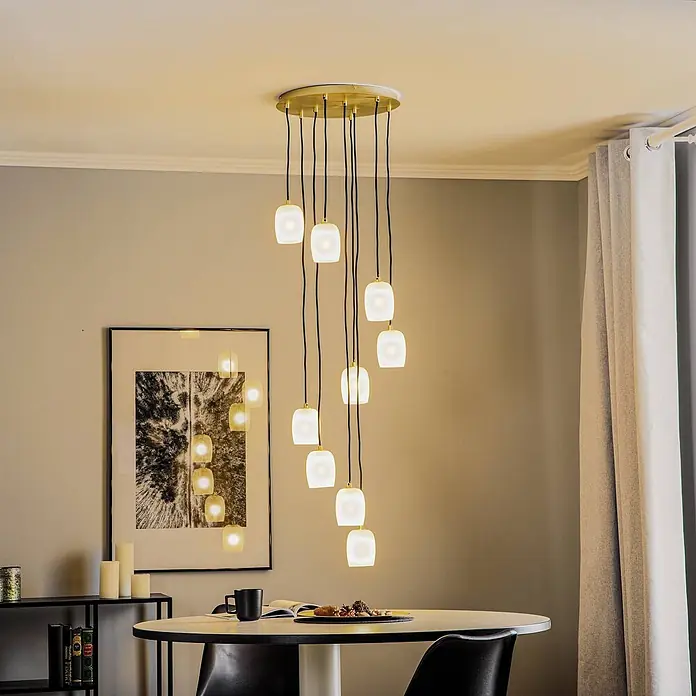 Lucande Pendelleuchte Taylan - L x B x H: 40 x 40 x 150 cm, weiß / opal, messing, sandweiß, G9 - Mehrflammiger Kronleuchter mit goldener Deckenplatte und weißen Milchglasschirmen über einem Esstisch.