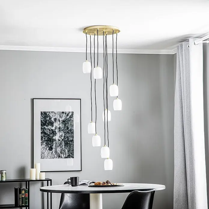 Lucande Pendelleuchte Taylan - L x B x H: 40 x 40 x 150 cm, weiß / opal, messing, sandweiß, G9 - Mehrflammige Pendelleuchte mit goldener Basis, schwarzen Kabeln und weißen Glasschirmen über einem Esstisch.