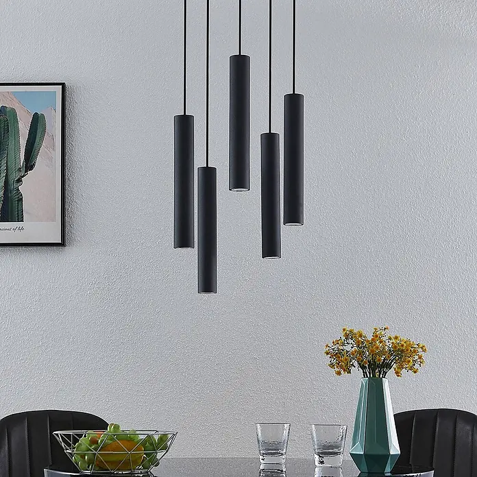 Lindby Pendelleuchte Sanad - L x B x H: 40 x 40 x 40 cm, schwarz, sandSchwarz, GU10 - Fünf schwarze zylindrische Pendelleuchten hängen in unterschiedlichen Höhen über einem Esstisch und beleuchten den Raum.