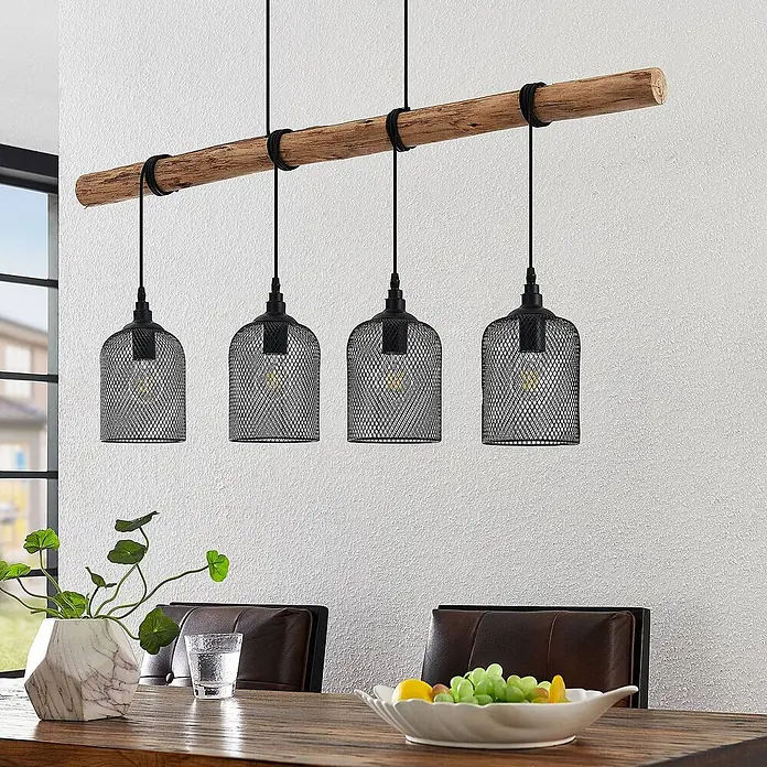 Lindby Pendelleuchte Elrond - L x B x H: 116 x 15 x 24,5 cm, schwarz, Schwarz matt, holz hell, E27 - Hängelampe aus Holzbalken mit vier schwarzen Drahtgeflecht-Pendelleuchten über einem Esstisch.