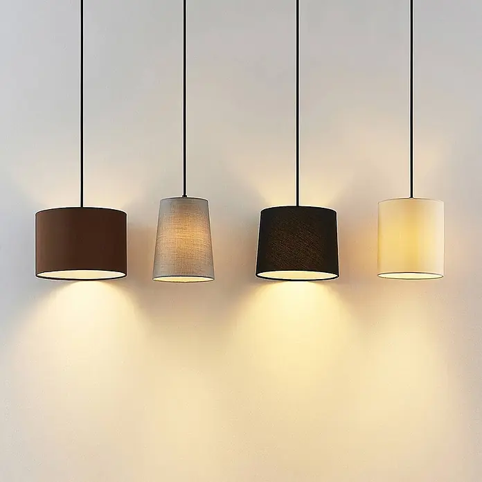 Lindby Pendelleuchte Amilia - Multicolour, Holz natur, Schwarz, grau, beige, braun, E27 - Vier Pendelleuchten mit Stoffschirmen in Braun, Grau, Schwarz und Creme, die eine Wand beleuchten.