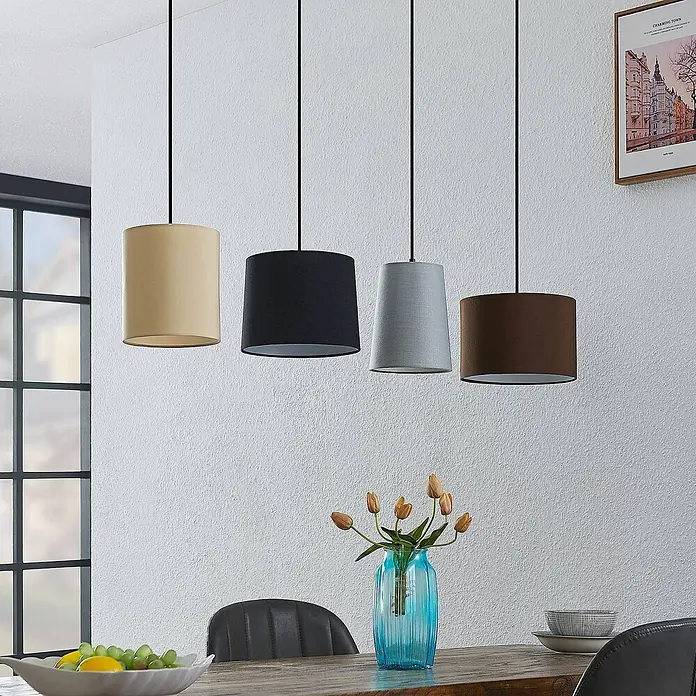 Lindby Pendelleuchte Amilia - Multicolour, Holz natur, Schwarz, grau, beige, braun, E27 - Vier Stoff-Pendelleuchten in Beige, Schwarz, Grau und Braun hängen über einem Holztisch.