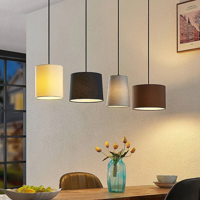 Lindby Pendelleuchte Amilia - Multicolour, Holz natur, Schwarz, grau, beige, braun, E27 - Vier Pendelleuchten aus Stoff: weiß zylindrisch, schwarz zylindrisch, grau konisch, braun zylindrisch, hängen über einem Esstisch.