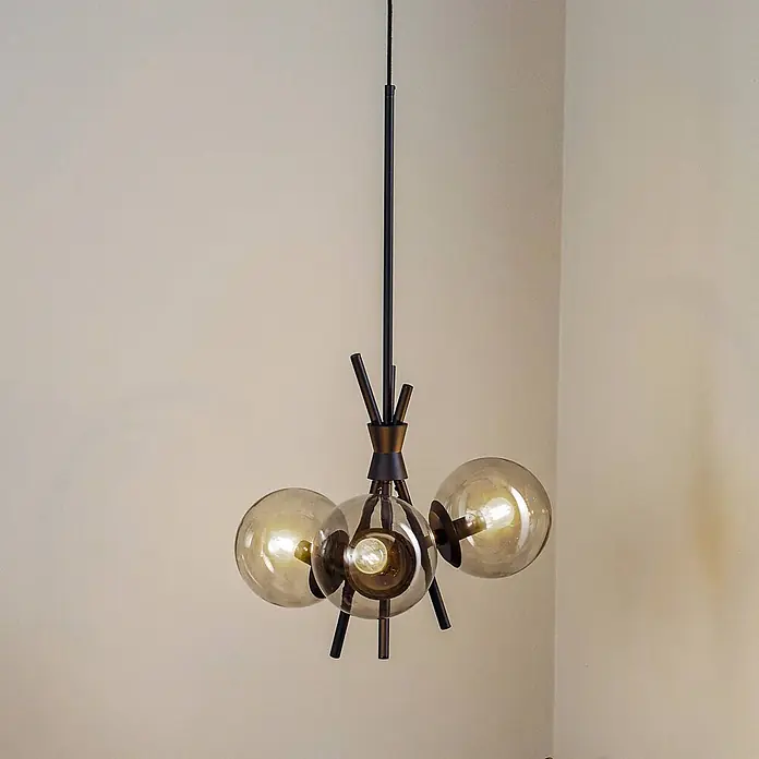Lucande Pendelleuchte Sotiana - alu / grau / zink, rauchgrau, Schwarz, E14 - Moderne Hängelampe mit drei bernsteinfarbenen Glaskugeln und dunklen Metallakzenten, von der Decke hängend.