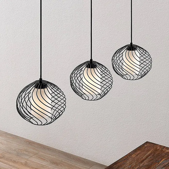 Lindby Pendelleuchte Cedrice - L x B x H: 108 x 25 x 21 cm, schwarz, Schwarz, weiß, E27 - Drei schwarze Pendelleuchten mit Drahtkäfig und weißen Diffusoren, hängen über einer Holzfläche.