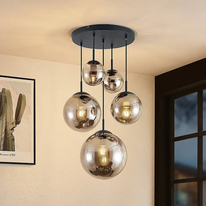 Lindby Pendelleuchte Teeja - L x B x H: 50 x 50 x 30 cm, alu / grau / zink, rauchgrau, Schwarz, E27 - Fünfflammige Pendelleuchte mit rauchfarbenen Glaskugeln und schwarzer Aufhängung, an runder Deckenhalterung in einem modernen Raum.