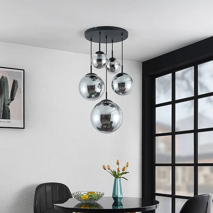 Lindby Pendelleuchte Teeja - L x B x H: 50 x 50 x 30 cm, alu / grau / zink, rauchgrau, Schwarz, E27 - Schwarze Pendelleuchte mit verchromten Glaskugeln in verschiedenen Größen, hängt über einem Esstisch in einem modernen Raum.