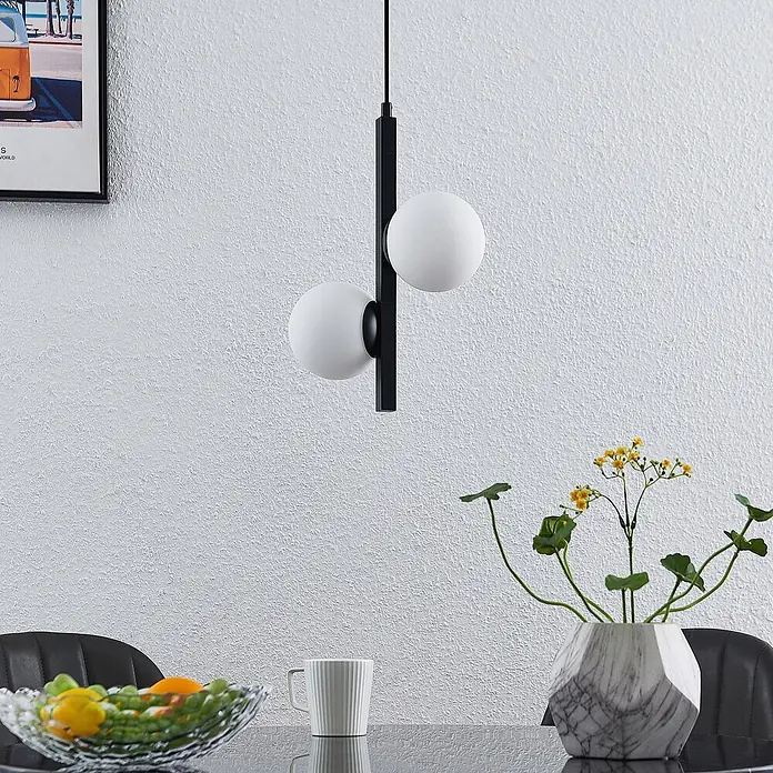 Lucande Pendelleuchte Emarin - L x B x H: 25 x 12 x 36,5 cm, Schwarz, opalweiß, G9 - Moderne schwarze Pendelleuchte mit zwei weißen Kugel-Diffusoren, hängt über einem Esstisch.