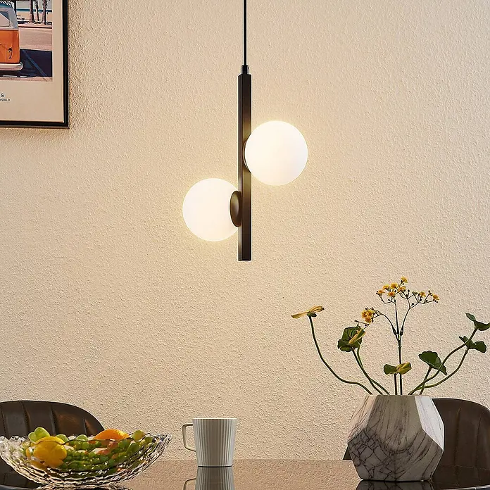 Lucande Pendelleuchte Emarin - L x B x H: 25 x 12 x 36,5 cm, Schwarz, opalweiß, G9 - Schwarze Pendelleuchte mit zwei kugelförmigen weißen Glasschirmen, über einem Esstisch hängend.