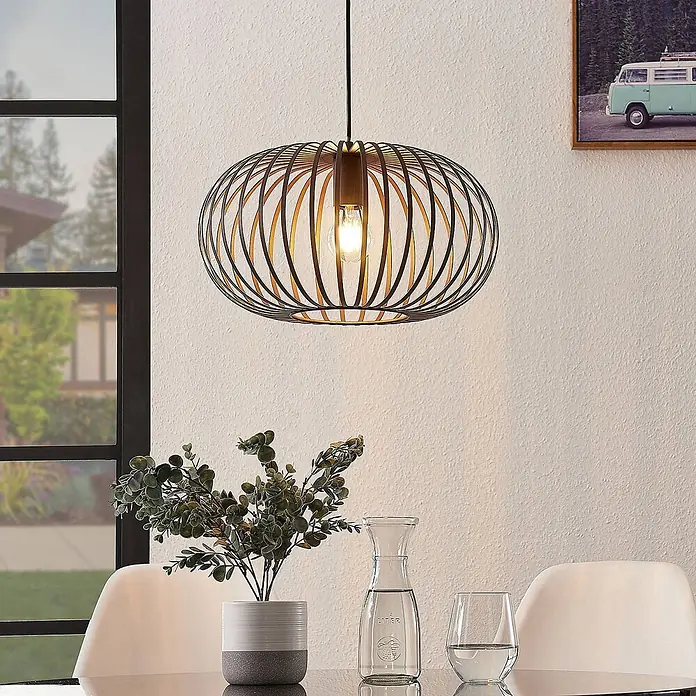 Lindby Pendelleuchte Nahele - braun / rost, kaffeebraun, E27 - Schwarze Pendelleuchte mit Metallkäfig, goldenem Inneren und sichtbarer Glühbirne über einem Esstisch.