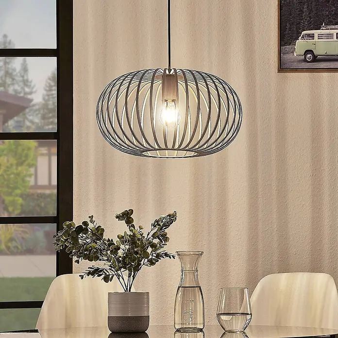 Lindby Pendelleuchte Nahele - braun / rost, kaffeebraun, E27 - Eine moderne Pendelleuchte mit schwarzem Metallkäfigschirm und freiliegender Glühbirne hängt über einem Esstisch.