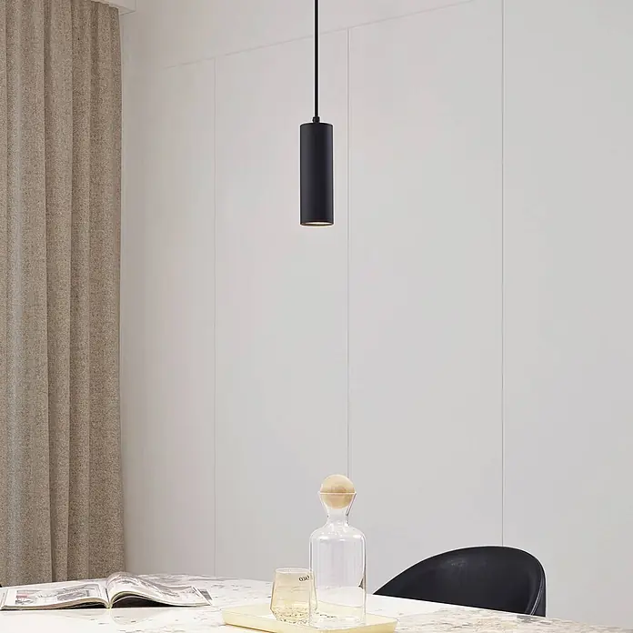 Lindby Pendelleuchte Joffrey - schwarz, Schwarz, GU10 - Schwarze zylindrische Pendelleuchte hängt über einem Tisch in einem modernen Interieur.