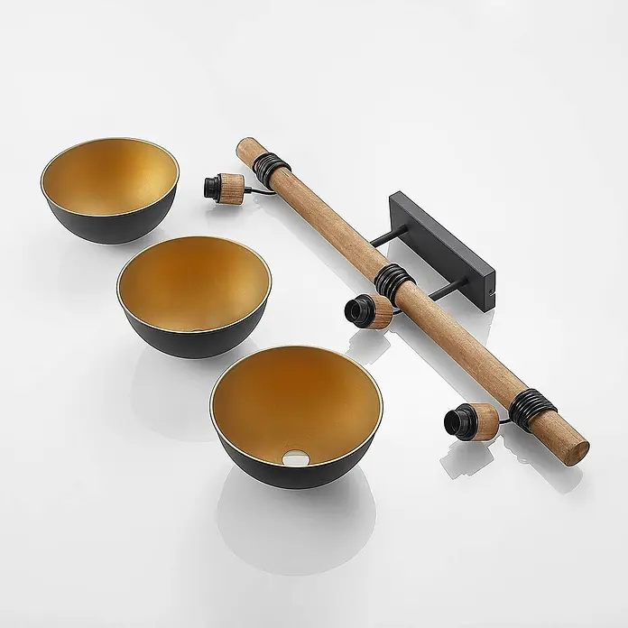 Lindby Pendelleuchte Flurin - schwarz, sandSchwarz, gold, holz, E27 - Drei schwarz-goldene schalenförmige Lampenschirme und eine Holzstange mit schwarzen Metallhalterungen und Lampenfassungen.