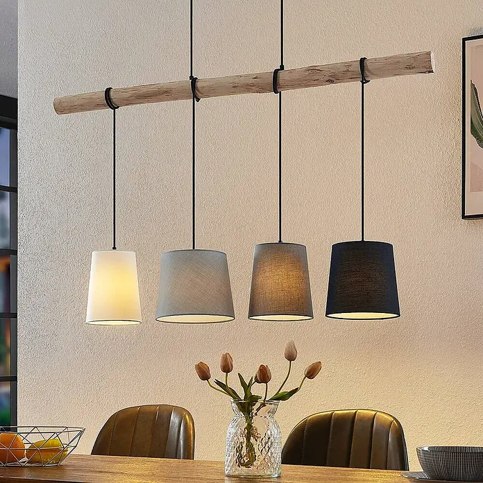Lindby Pendelleuchte Hinai - L x B x H: 116 x 23 x 22 cm, weiß / opal, Holz hell, Schwarz, grau, weiß, E27 - Hängelampe mit Holzbalken und vier Stoffschirmen (weiß, hellgrau, mittelgrau, dunkelgrau) über einem Esstisch.