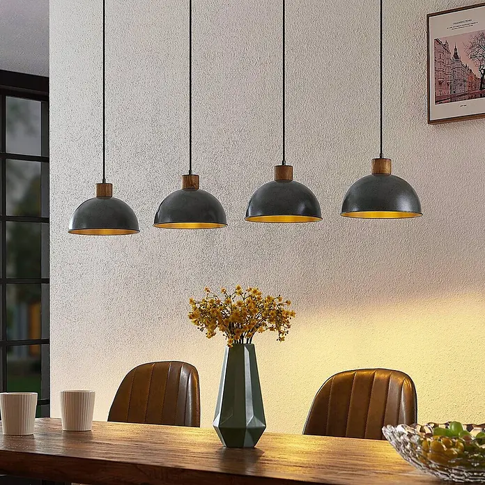 Lindby Pendelleuchte Durbis - L x B x H: 116 x 25 x 180 cm, schwarz, Holz natur, dunkelgrau, E27 - Vier dunkelgraue Kuppel-Pendelleuchten mit Holzaufsätzen und goldenen Innenseiten, die warmes Licht über einen Tisch abgeben.